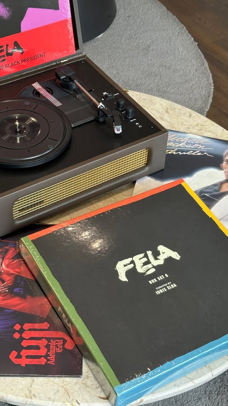 Vintage brown record player on a marble table surrounded by vinyl record albums.