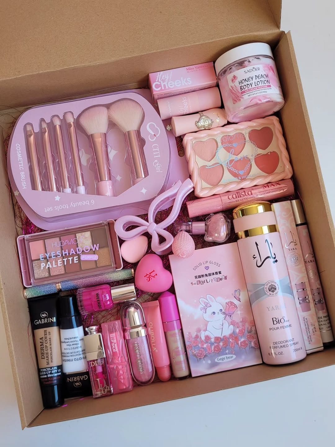 Beauty gift box filled with pink makeup, skincare products, and makeup brushes.