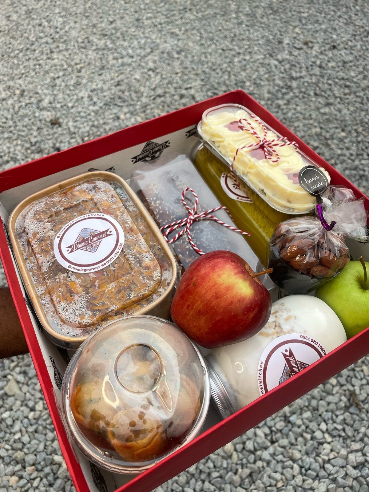 Gourmet food gift hamper in a red box with fruit and treats.