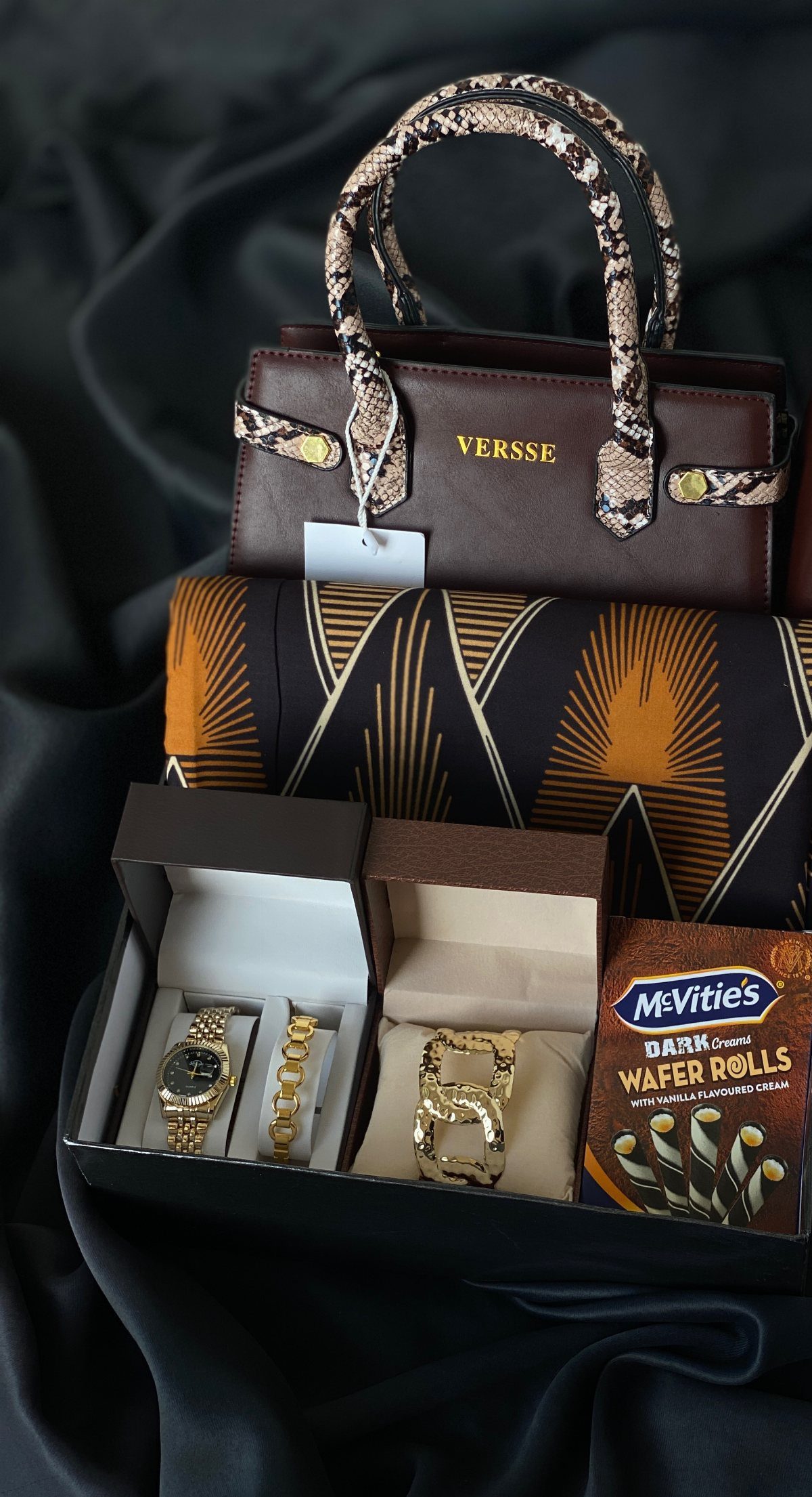 Gift set with brown handbag, gold watch, gold bracelet, and wafer rolls.