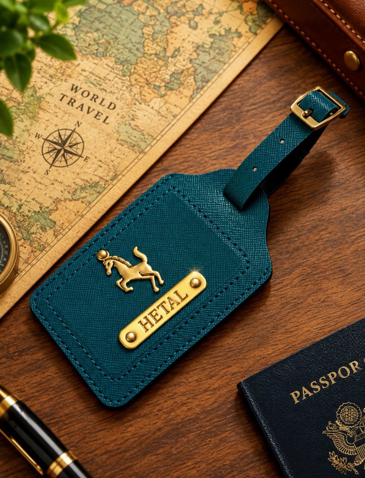 Teal leather luggage tag with gold nameplate and horse emblem on wooden table
