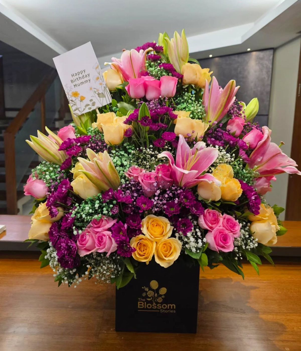 Large colorful bouquet of pink lilies and yellow roses in a black box.