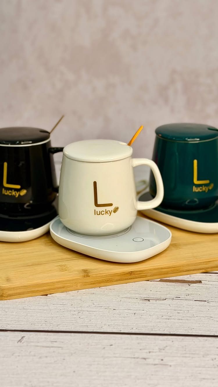 Three personalized ceramic mugs with lids on warming coasters on a wooden board.