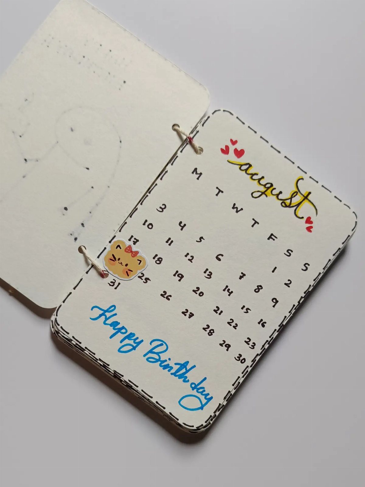Handmade August calendar with a cute cat and Happy Birthday message in blue.