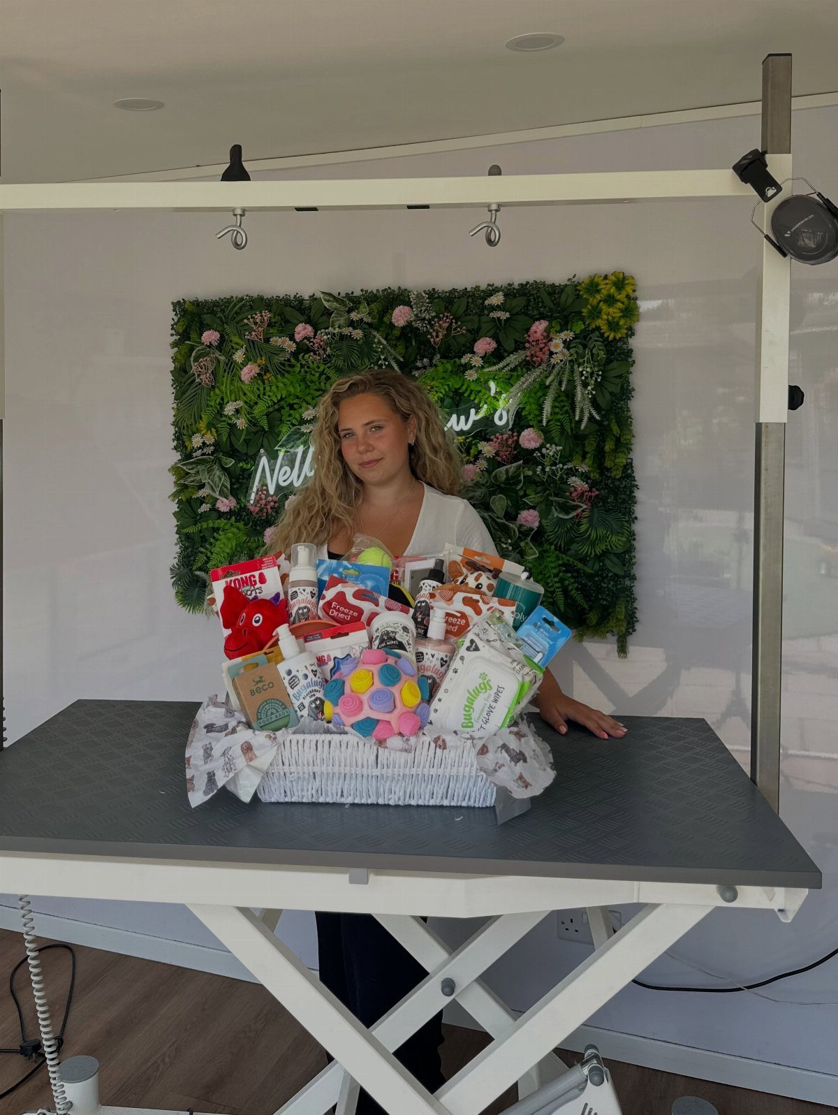 Woman presenting a large gift basket filled with colorful pet toys and supplies.