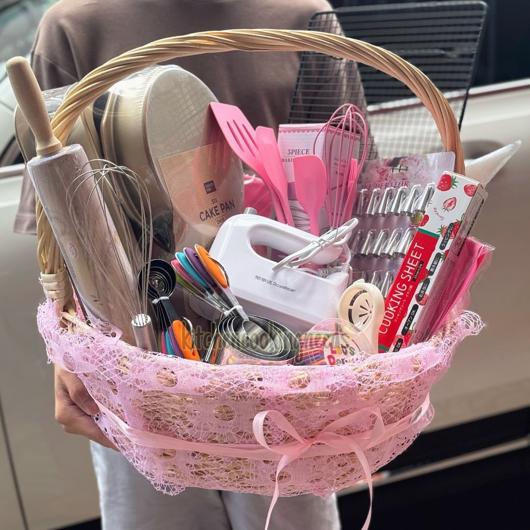 Baking gift basket with pink lace, containing a hand mixer, whisks, and spatulas.