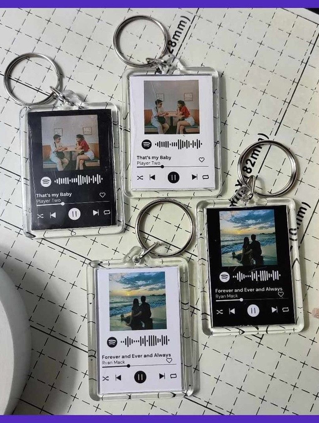 Four acrylic keychains featuring personalized photos and music playback bars on a grid mat.