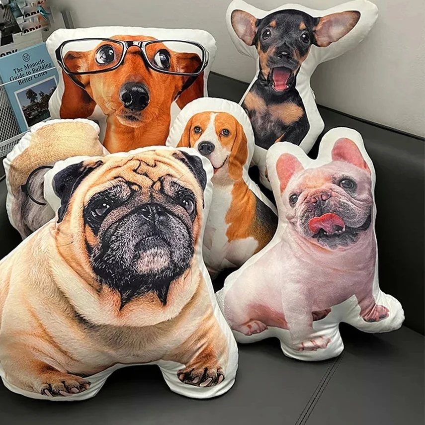 Custom shaped pillows with printed dog faces resting on a dark grey sofa.