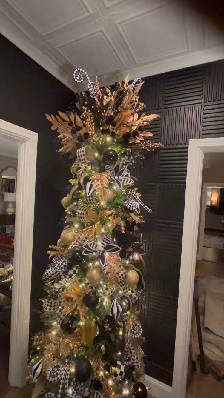 Black Christmas tree decorated with gold ornaments and black and white ribbons.