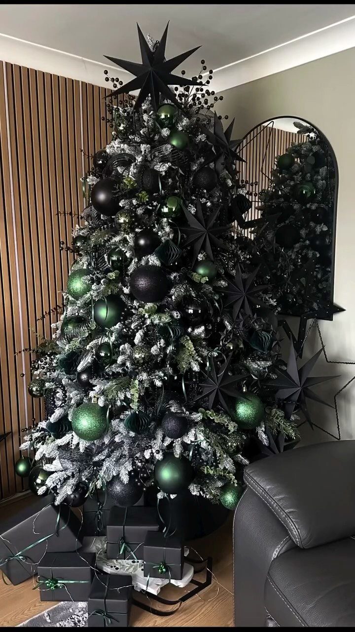 Black Christmas tree decorated with green and black ornaments and a star topper.