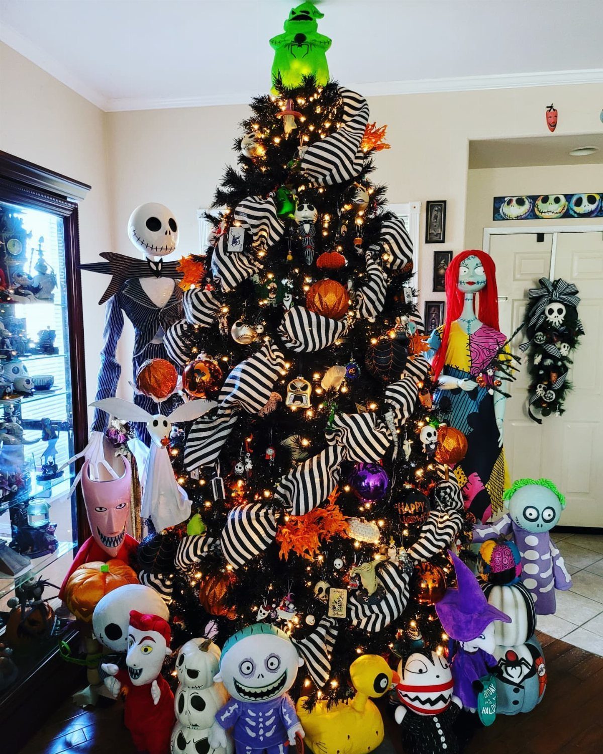 Black Christmas tree decorated with Nightmare Before Christmas characters and striped ribbons.