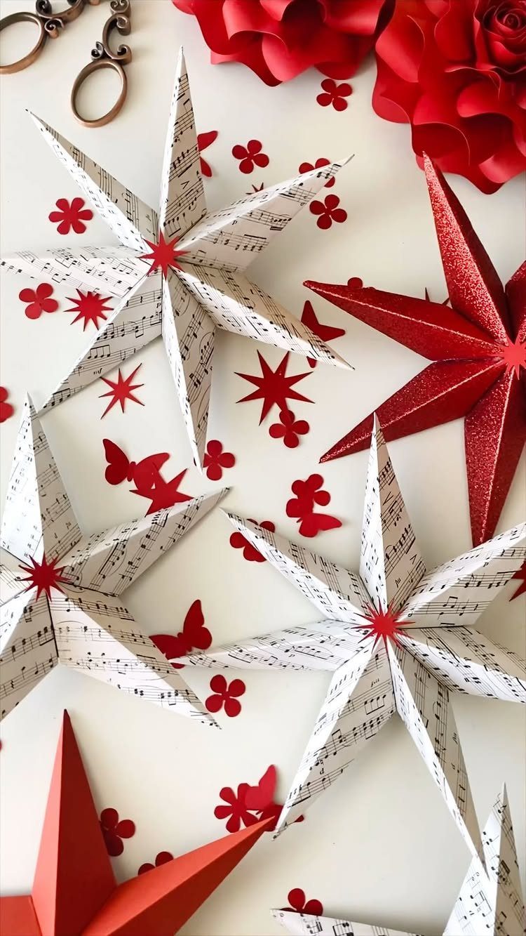 3D folded paper stars made from red and sheet music paper on white background