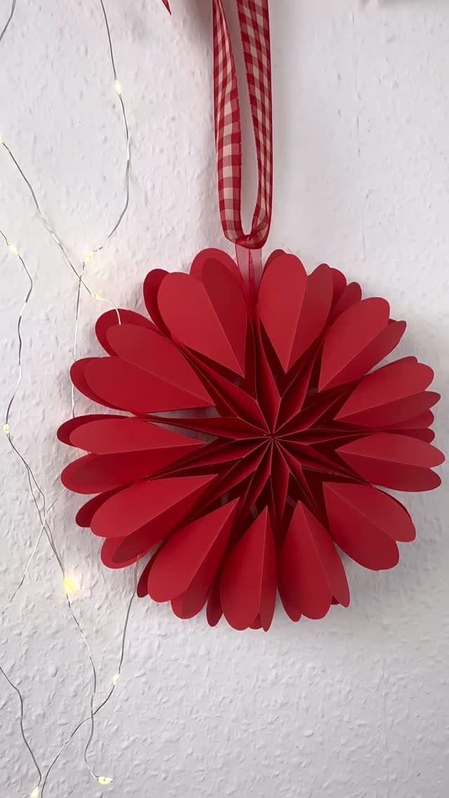 Red paper ornament made of heart cut-outs hanging from a checkered ribbon.