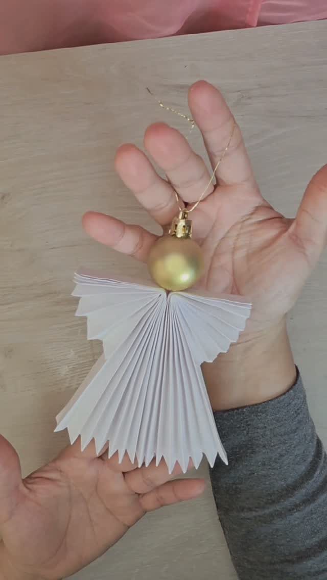 Handmade angel ornament with pleated white paper body and gold bead head.