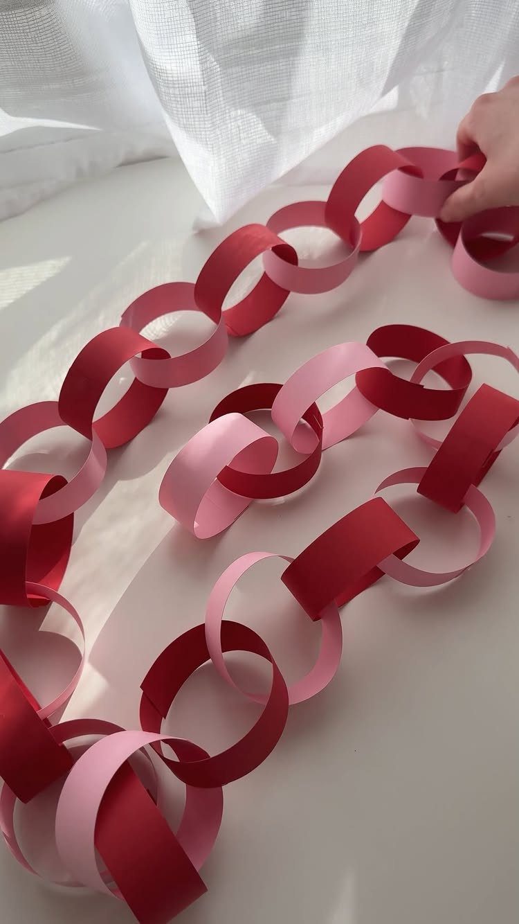 Red and pink paper chain loops resting on a white surface.