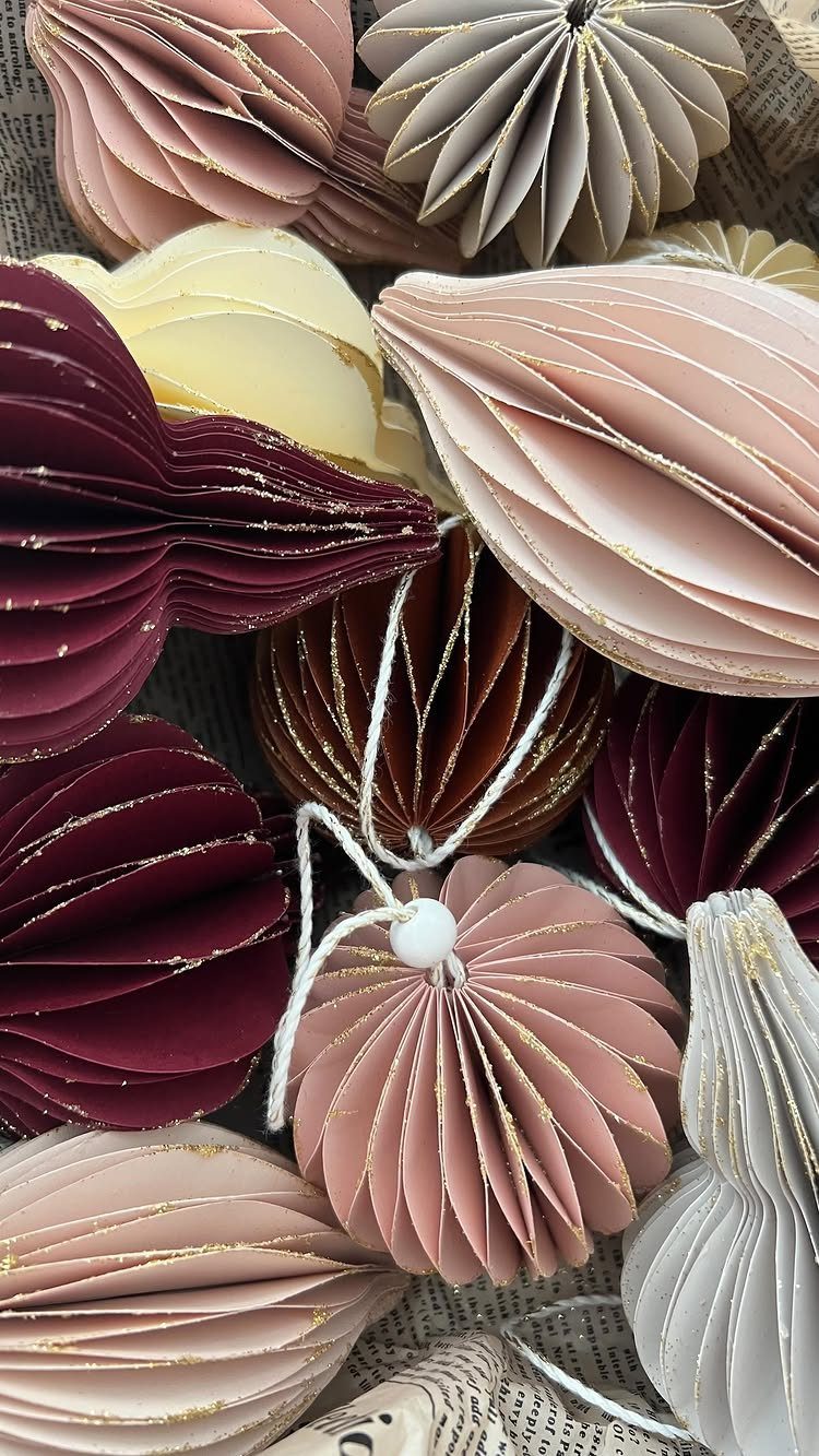 Pleated paper ornaments in burgundy, gold, and pink with glittery edges.
