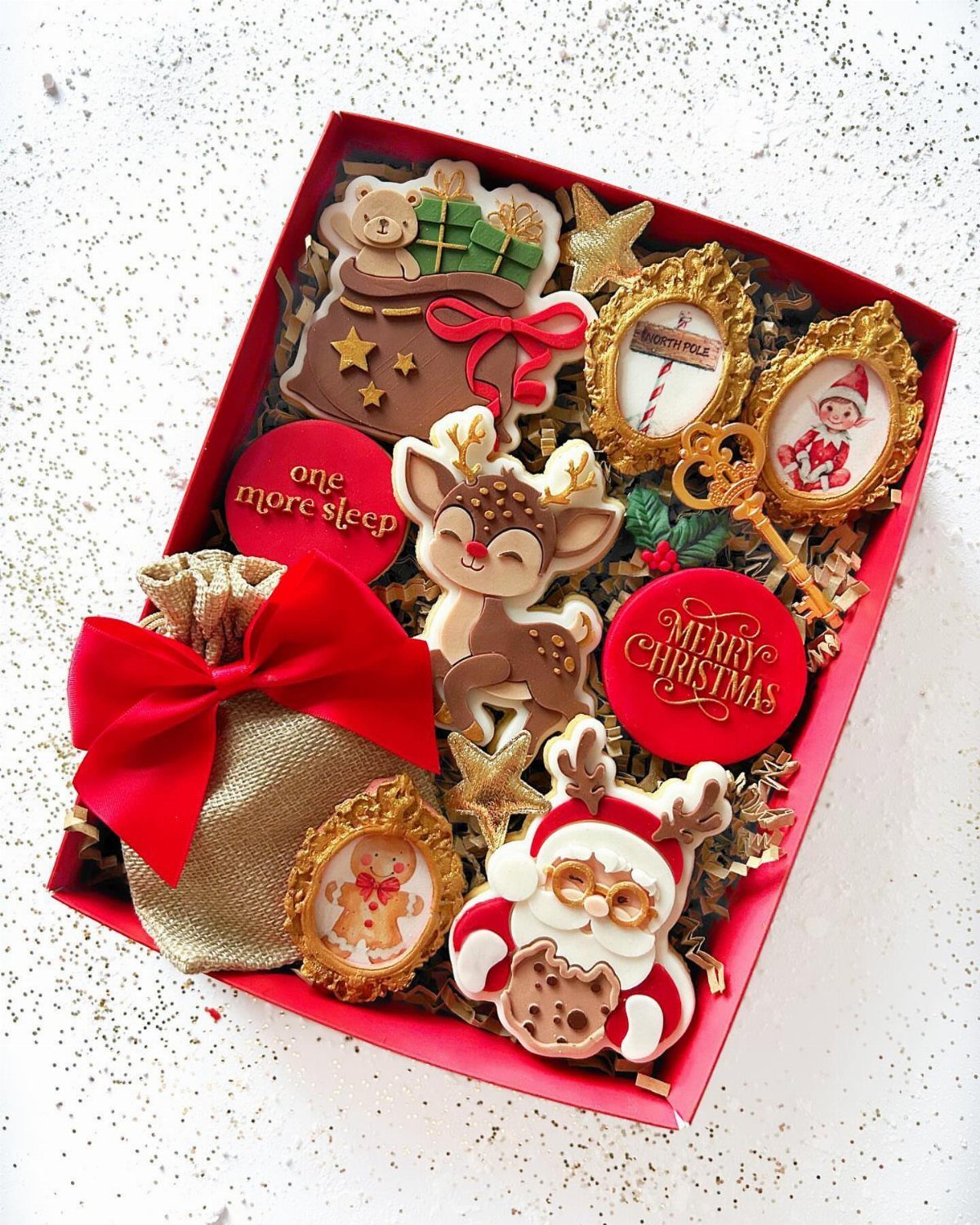 Decorated Christmas cookies and a gold pouch inside a red gift box.