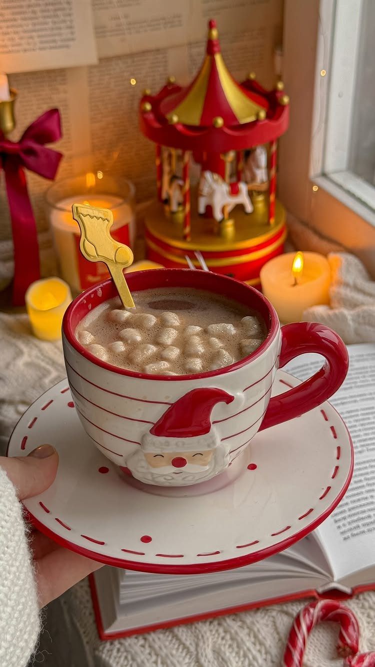 Hot chocolate with marshmallows in a Santa mug surrounded by festive holiday decorations.