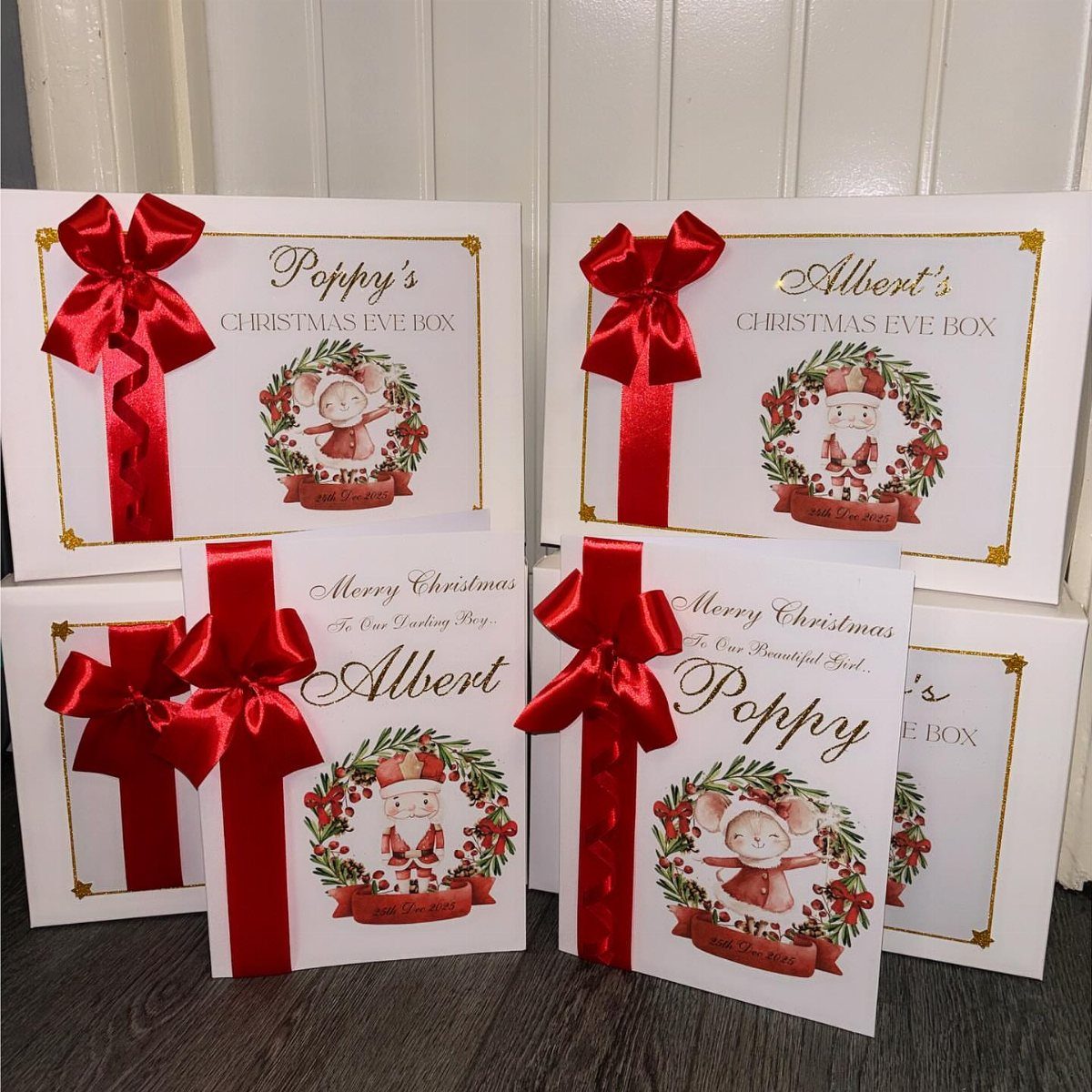 Four personalized white Christmas Eve boxes with red bows and festive animal illustrations.