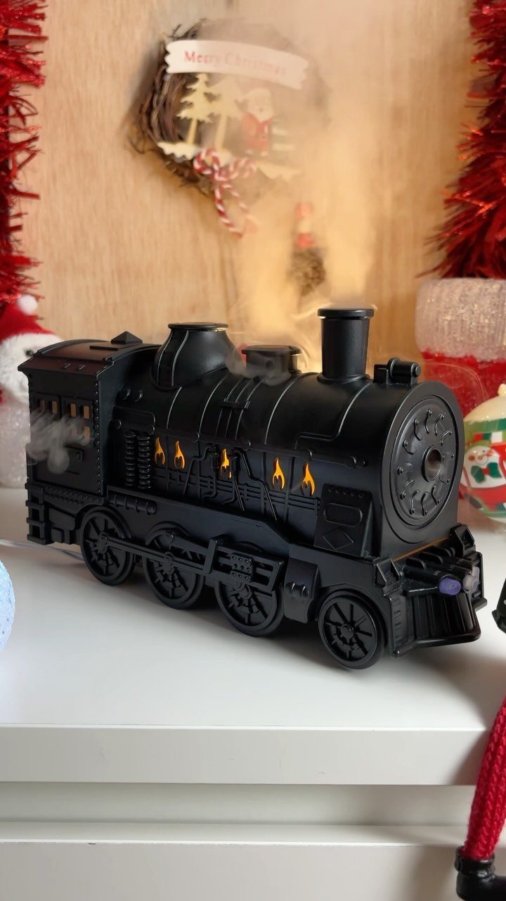 Black toy steam locomotive on a white surface with Christmas decorations in background