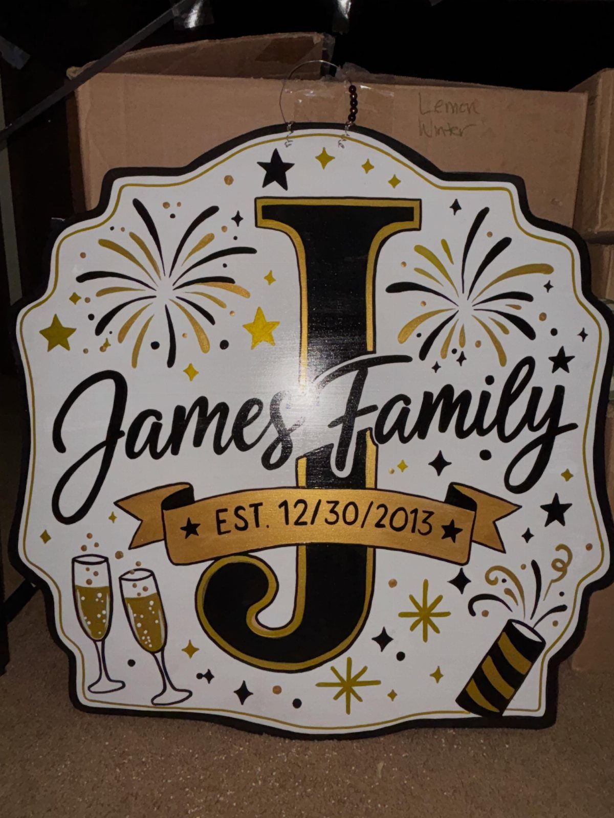 Personalized white wooden sign for the James Family with gold and black decorations.