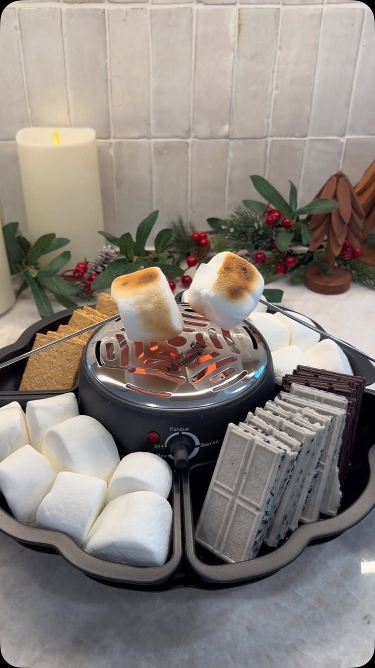 Electric indoor s'mores maker with toasted marshmallows, chocolate, and graham crackers on counter