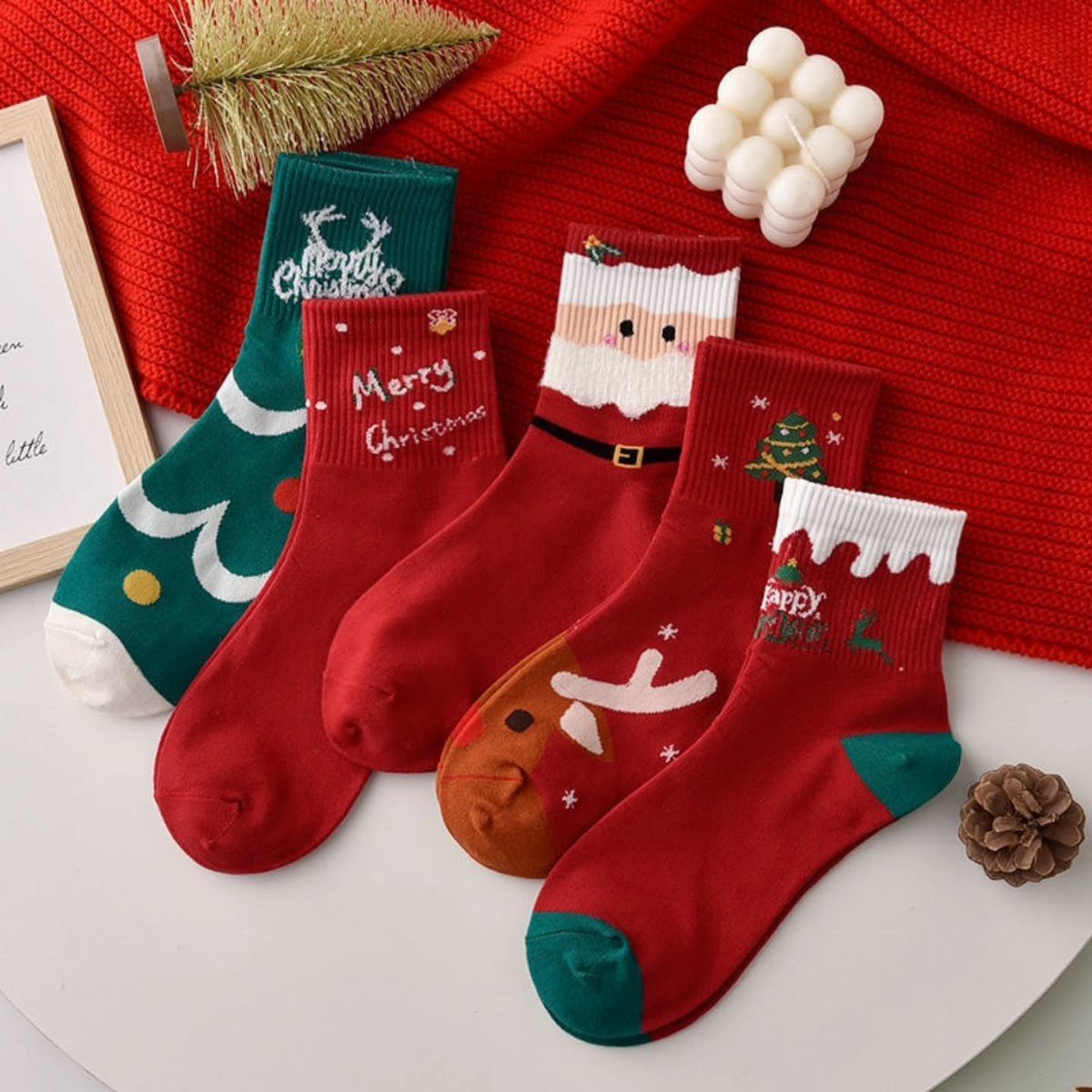 Christmas-themed socks in red and green arranged on a white surface with decorations.
