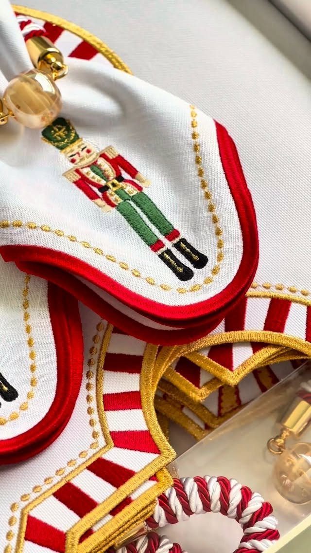 White embroidered nutcracker napkins with red and gold borders and gold napkin rings.