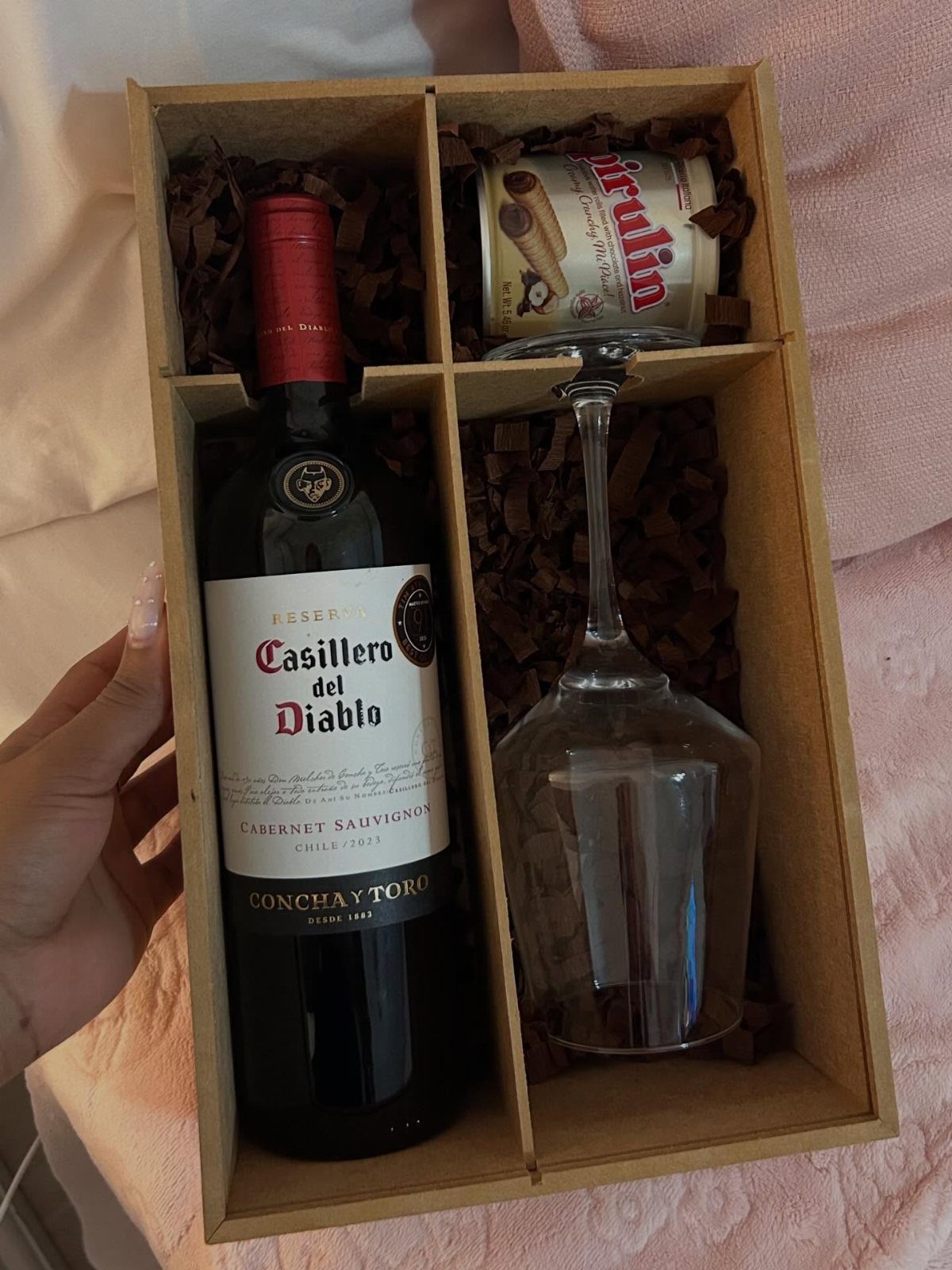 Wine bottle and upside-down glass with wafers in a cardboard gift box