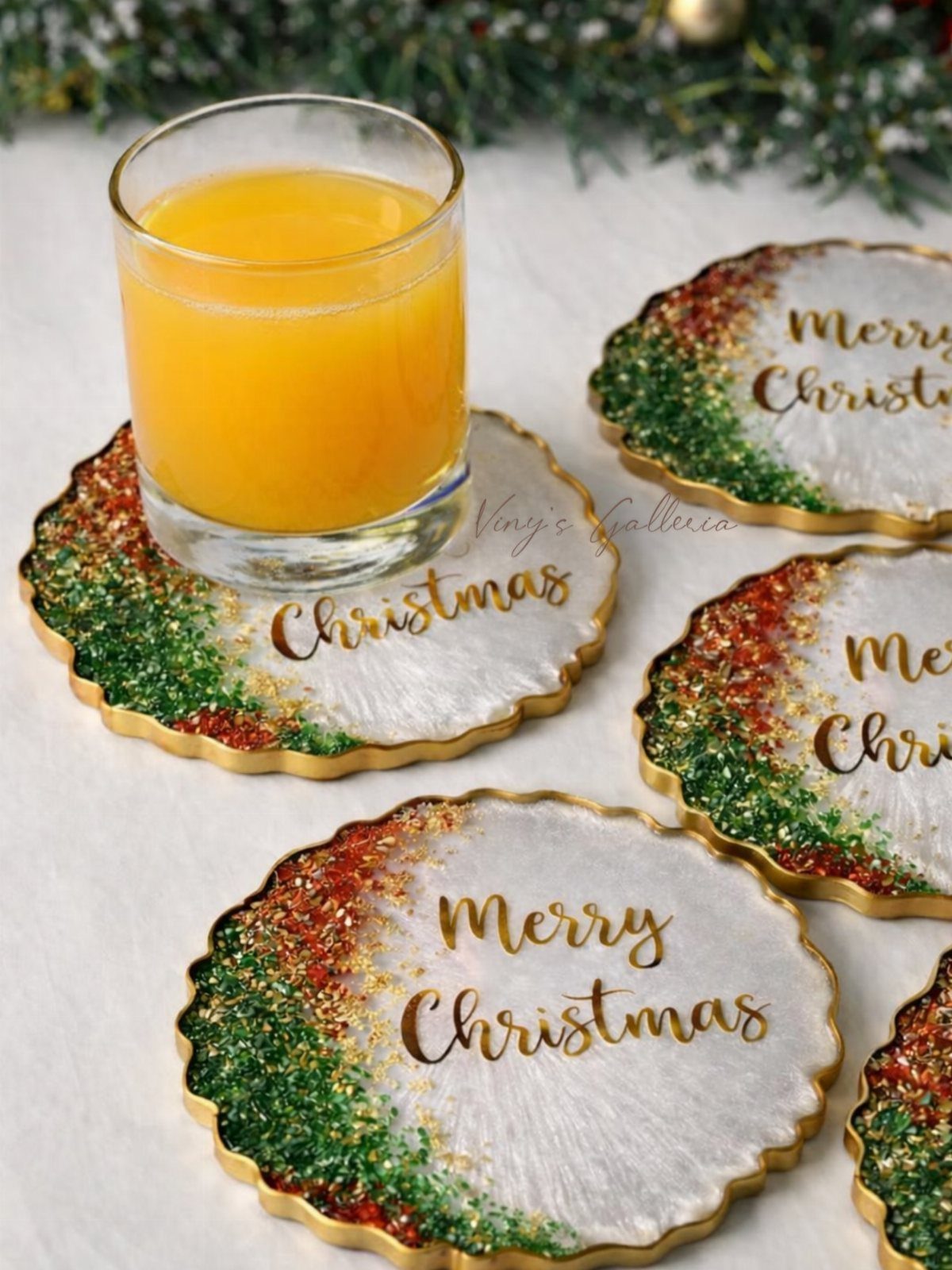 Christmas coasters with red and green glitter and a glass of orange juice