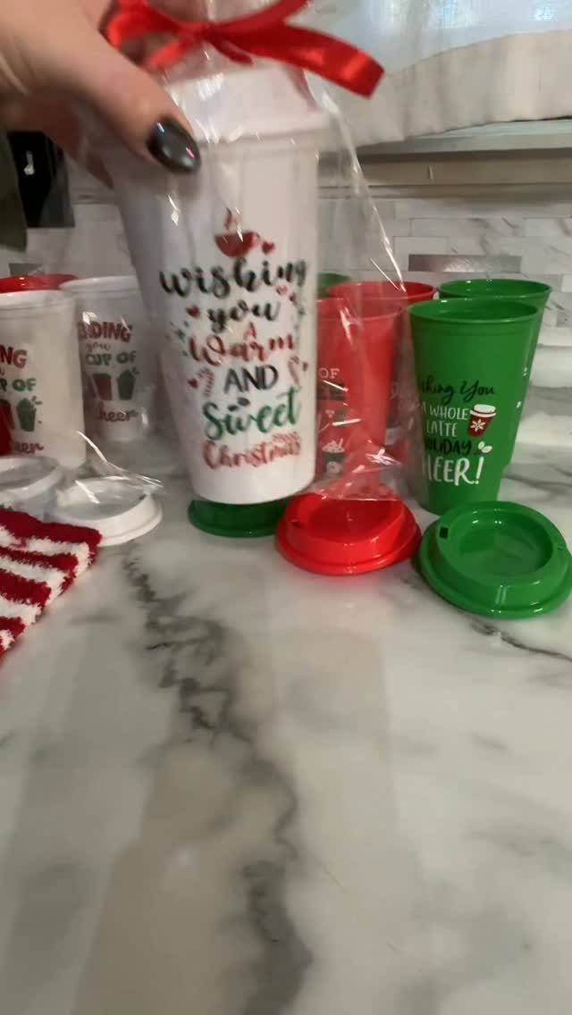 Festive white, red, and green tumblers wrapped as Christmas gifts on marble.