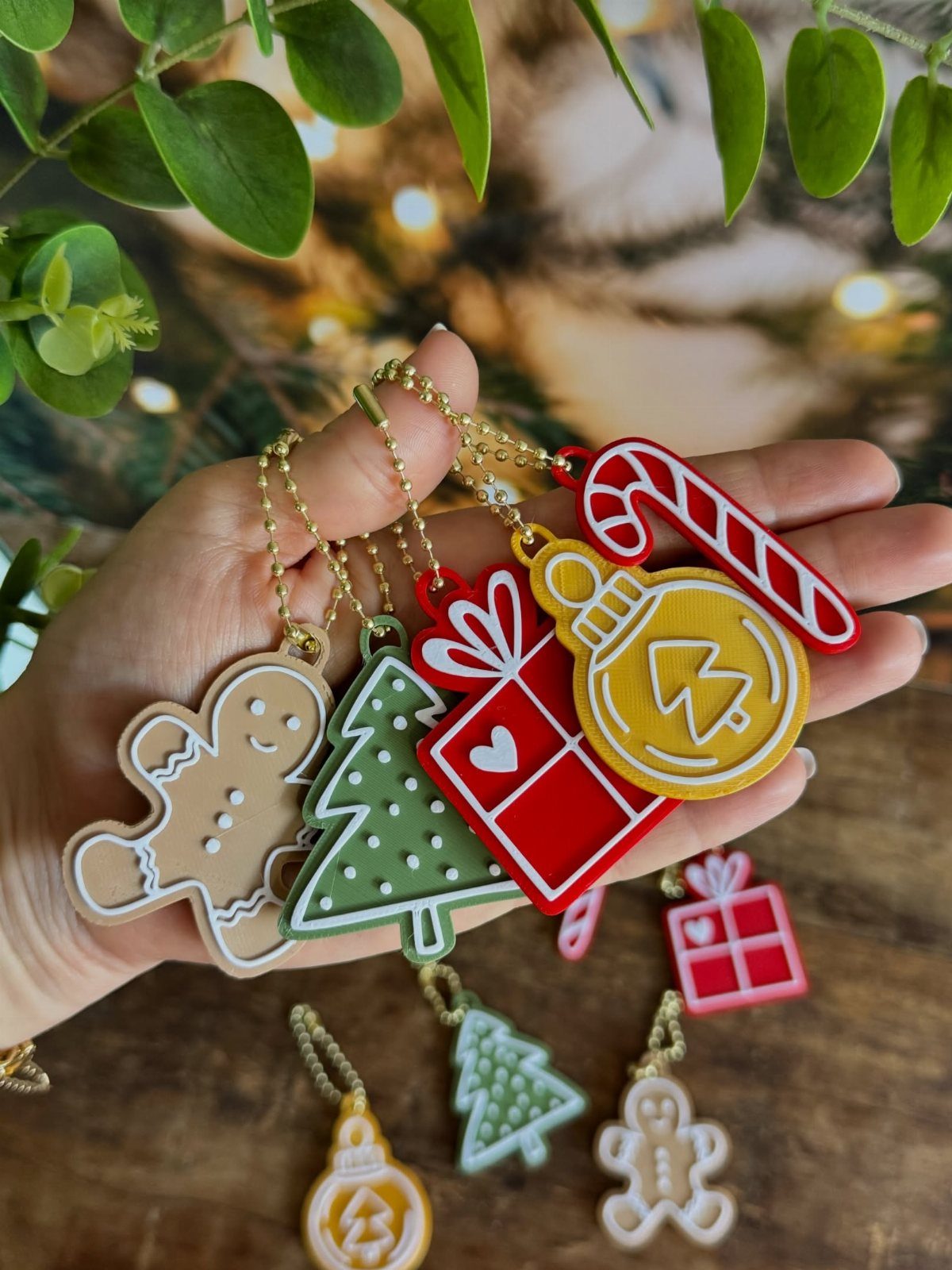 Colorful holiday ornaments including a gingerbread man and Christmas tree held in a hand.