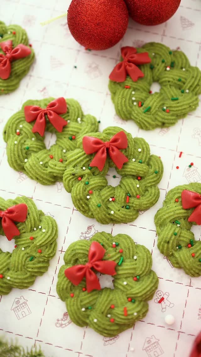 Green wreath cookies with red bows and sprinkles on a festive white background