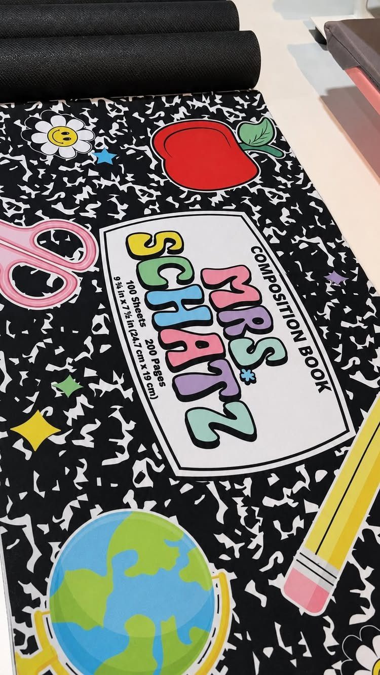 Personalized desk mat with school icons and a composition book label for Mrs. Schatz