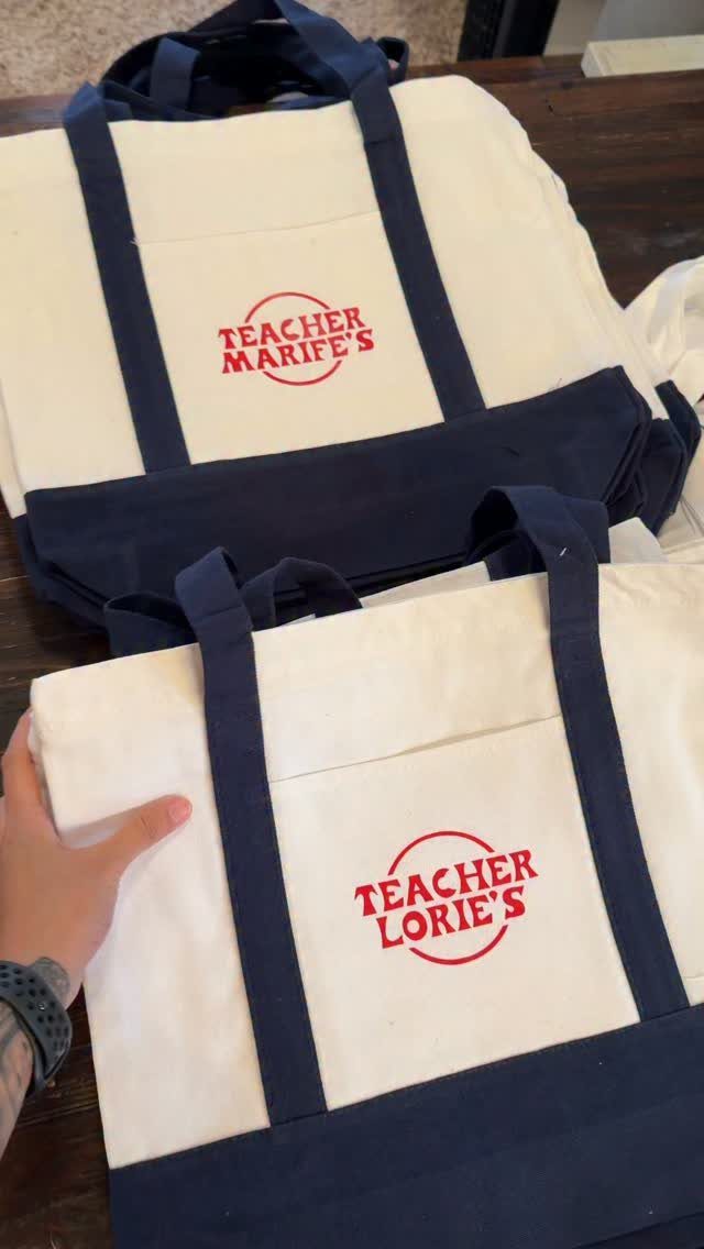 Two personalized canvas tote bags for teachers with red text and navy straps.