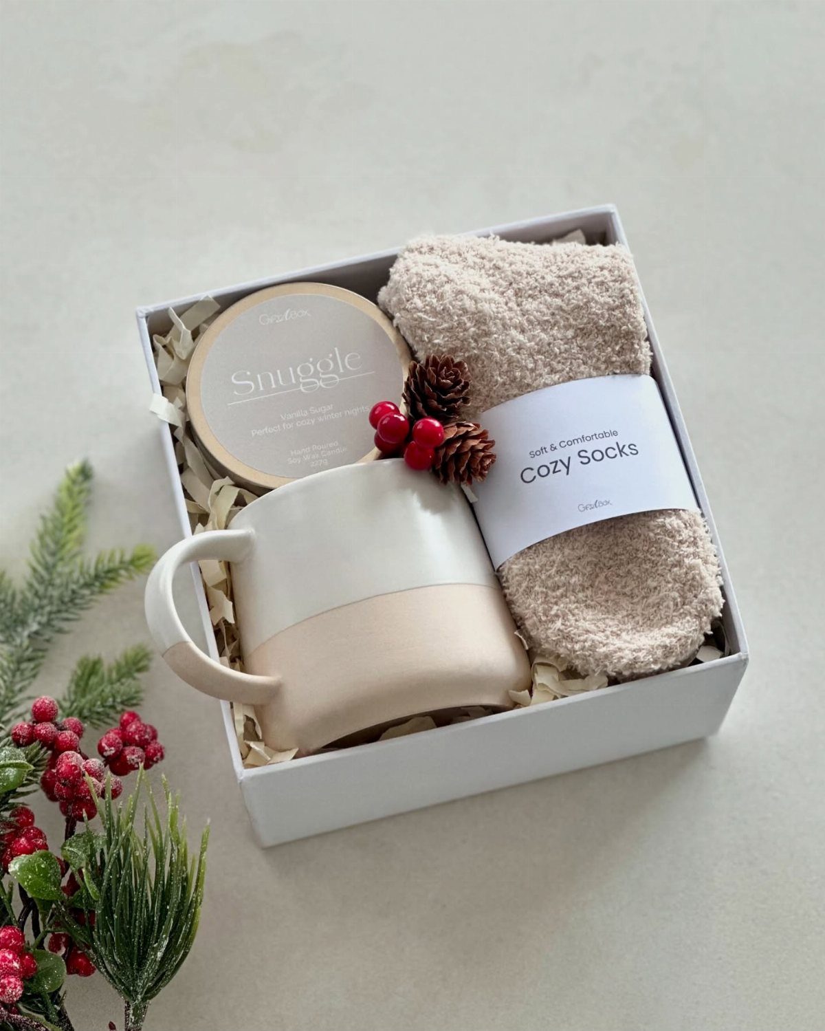 Gift box with a beige mug, fluffy socks, and a candle for Christmas.