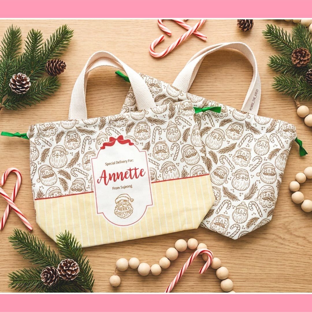 Personalized Christmas tote bags with Santa prints on a wooden table with decorations