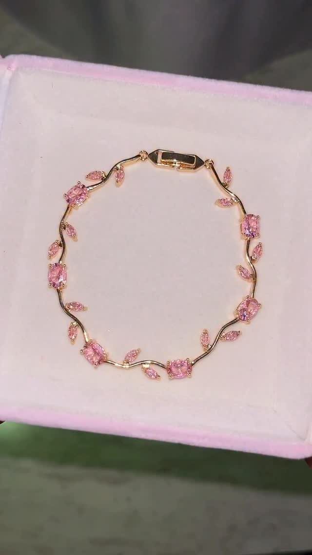 Gold bracelet with pink gemstones and leaf accents in a pink velvet box