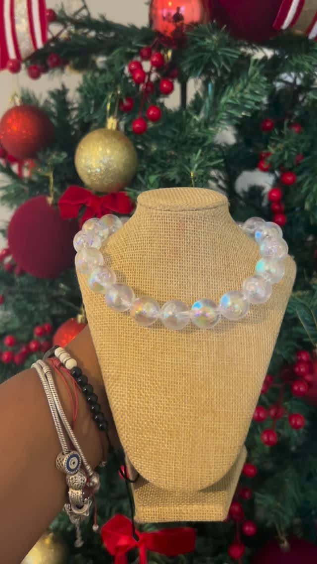 Iridescent beaded necklace on a jewelry bust in front of a decorated Christmas tree