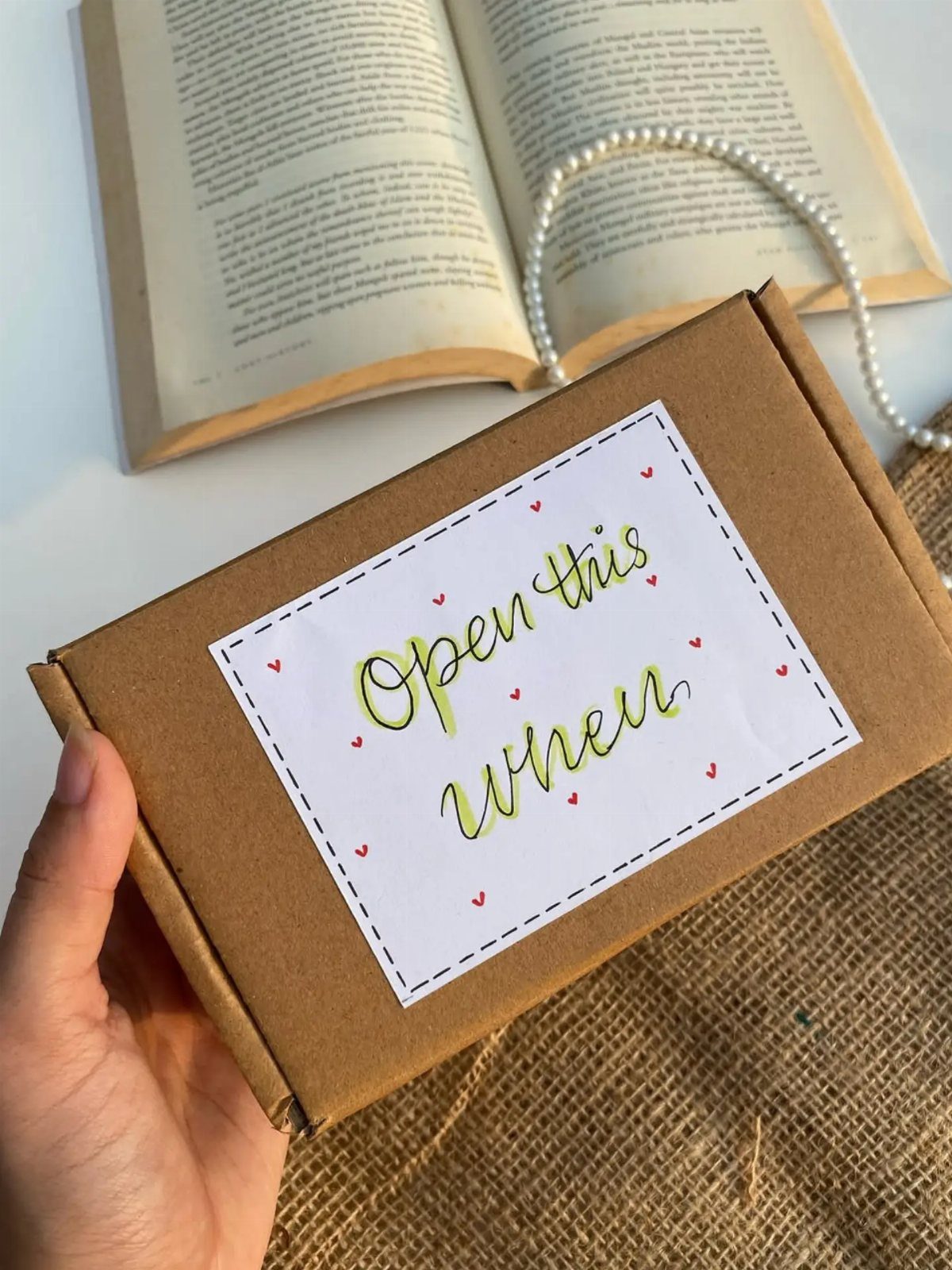 Brown cardboard gift box with 'Open this when' label held by a hand.
