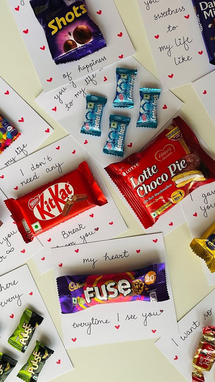 Assorted chocolate bars on white cards with handwritten romantic messages and red hearts.