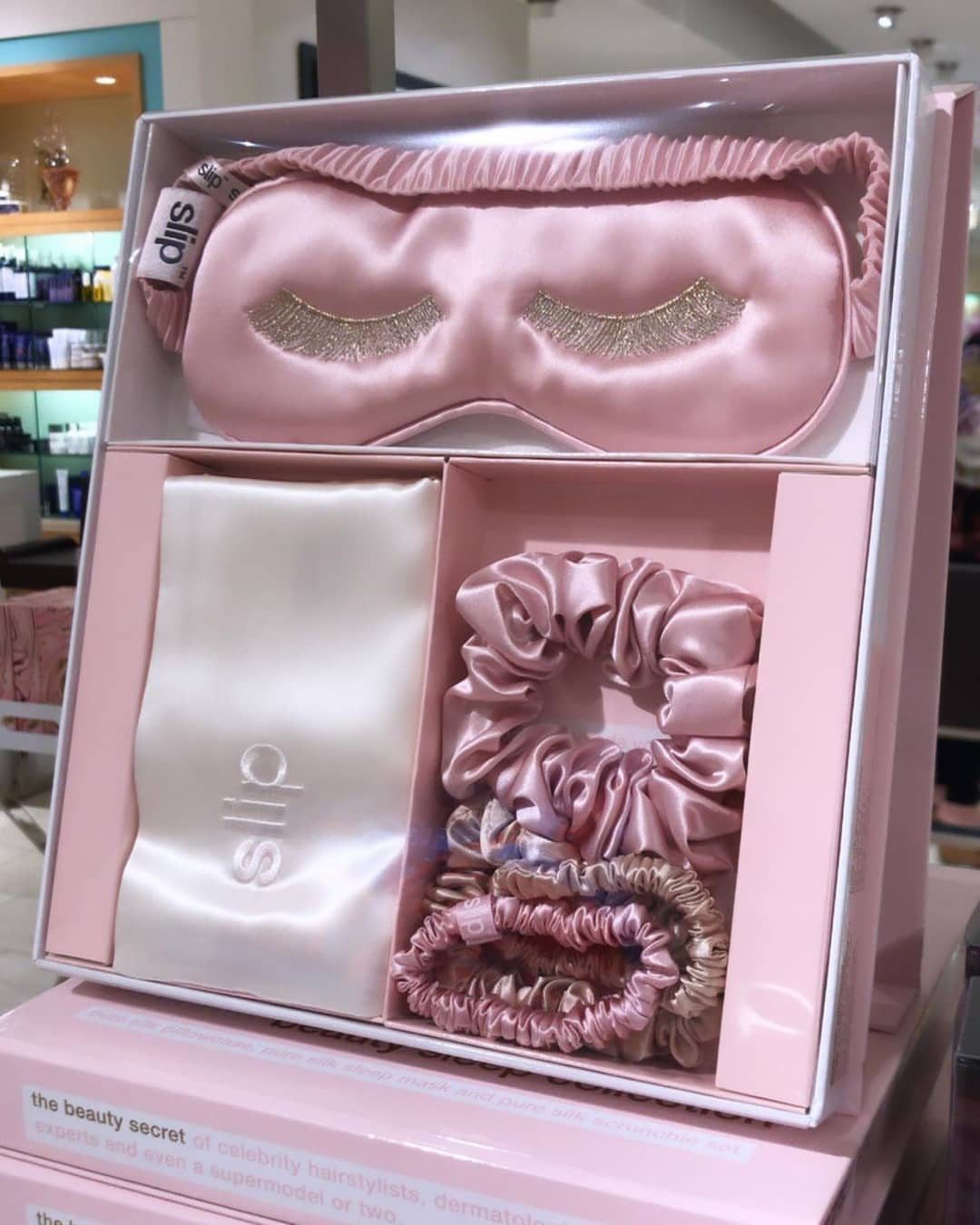 Pink silk sleep mask, scrunchies, and pouch in a white gift box.