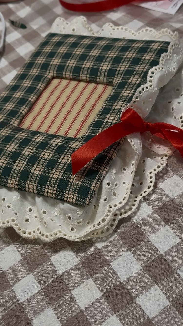 Handmade plaid fabric picture frame with a red bow on white lace doily.