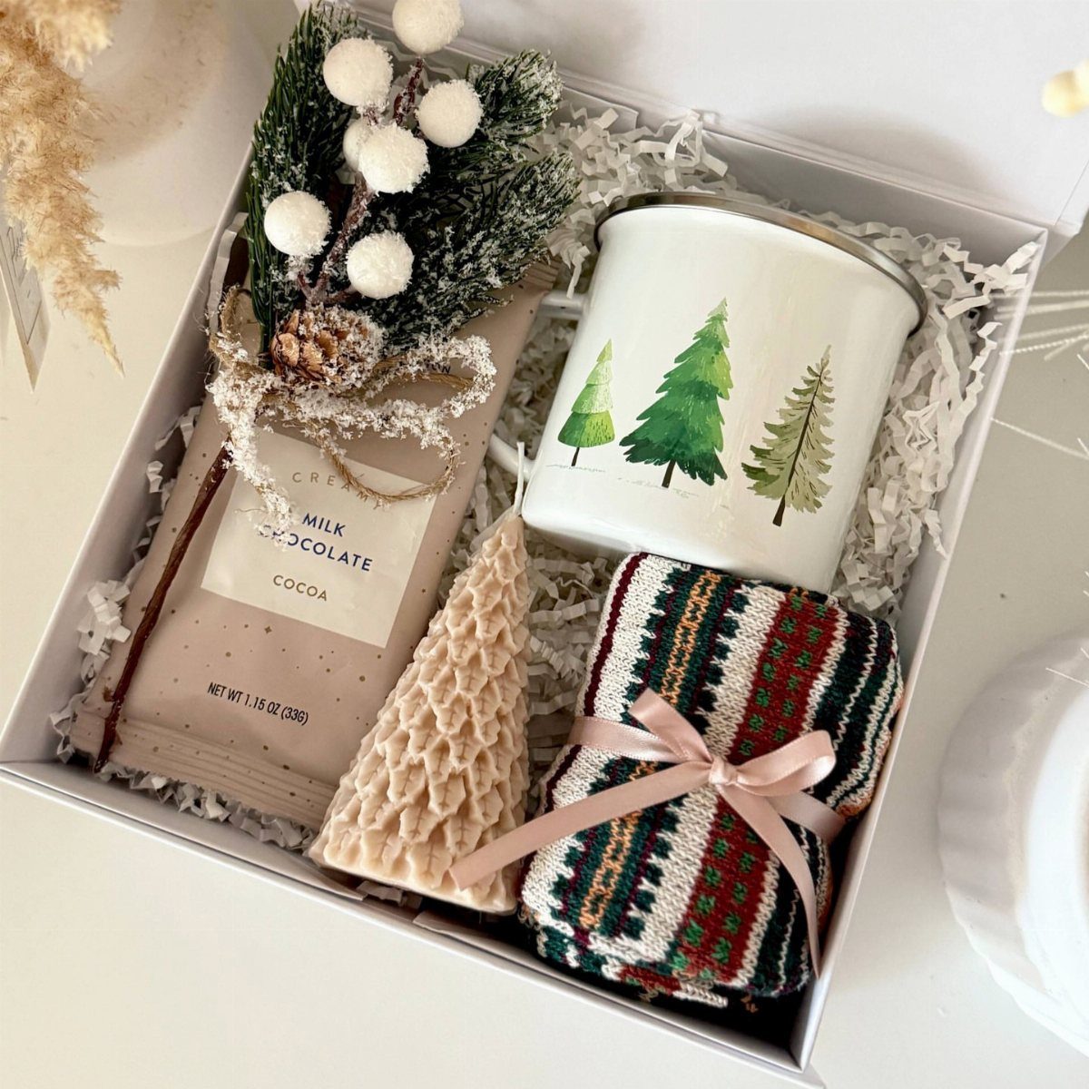 Gift box containing chocolate, a pine tree mug, and a patterned textile.