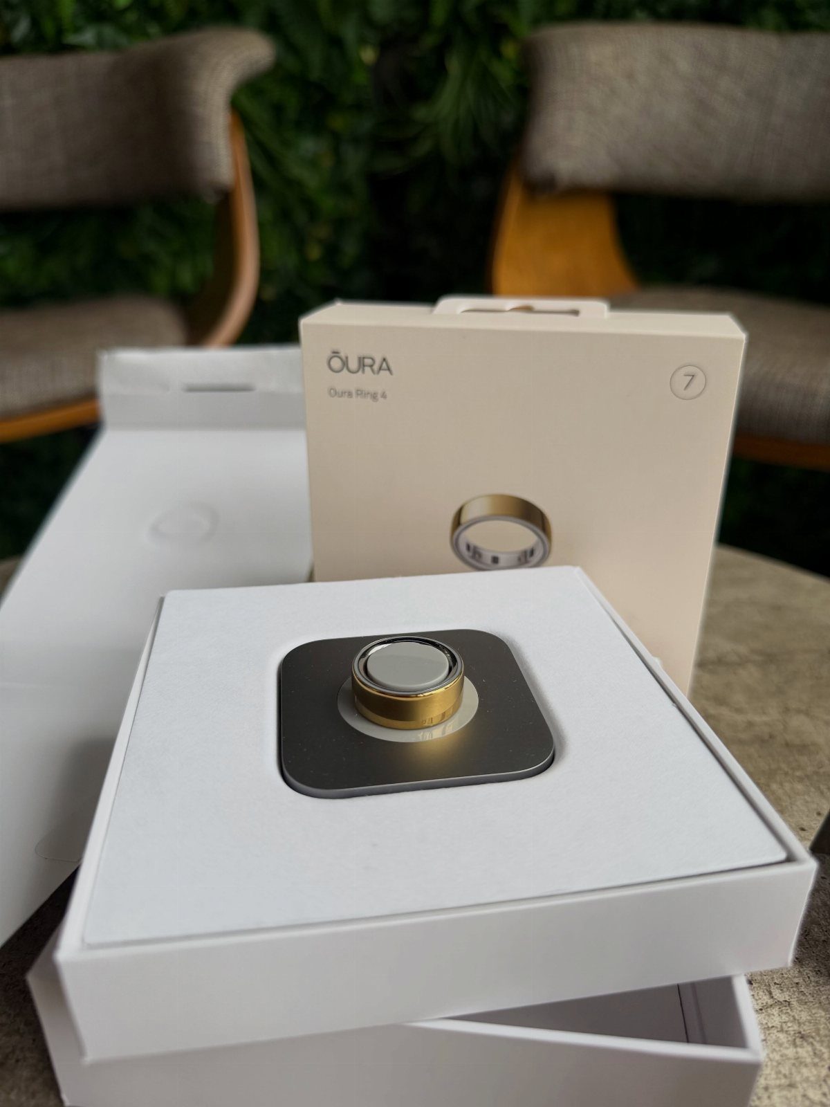 Gold Oura smart ring in its white packaging on a light table