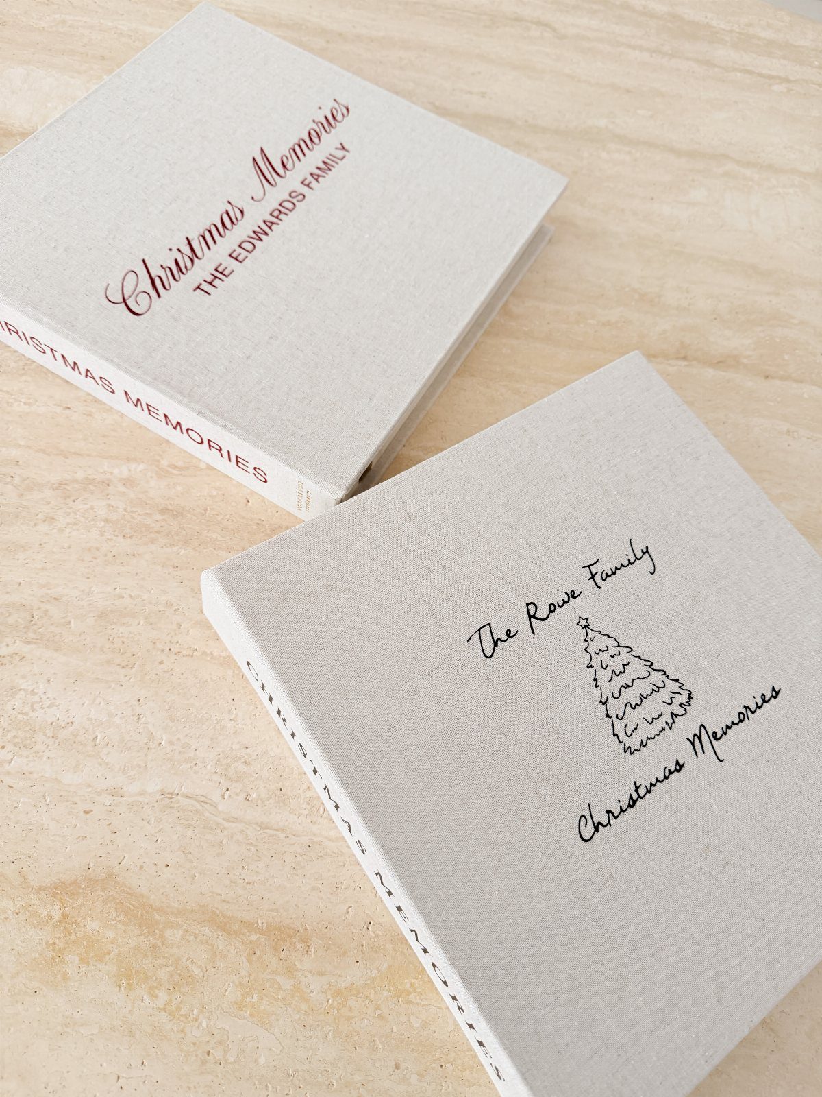 Two linen photo albums with personalized Christmas memories text on a stone surface.