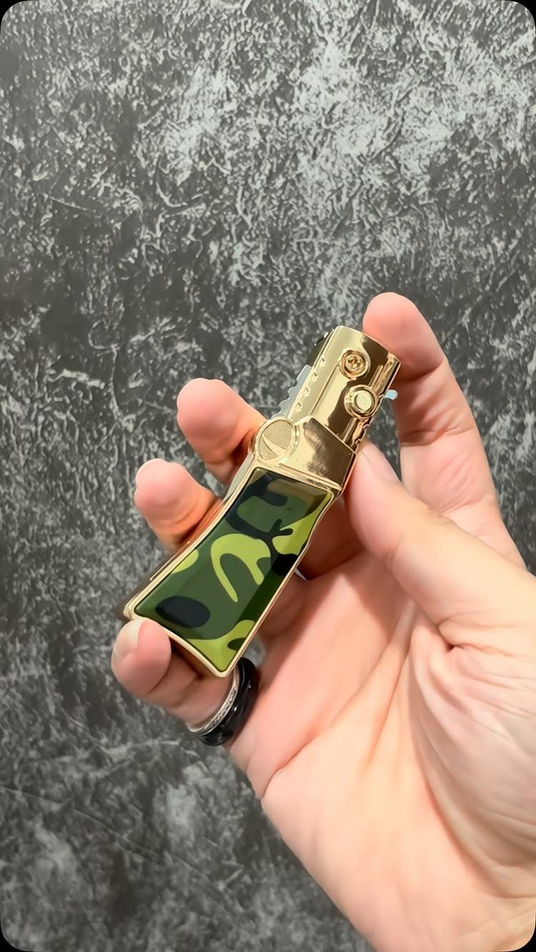 Gold lighter with green camouflage pattern held in a person's hand