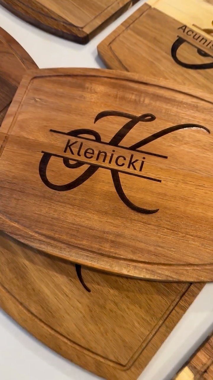 Wooden cutting boards with personalized engravings of names and large cursive initials.