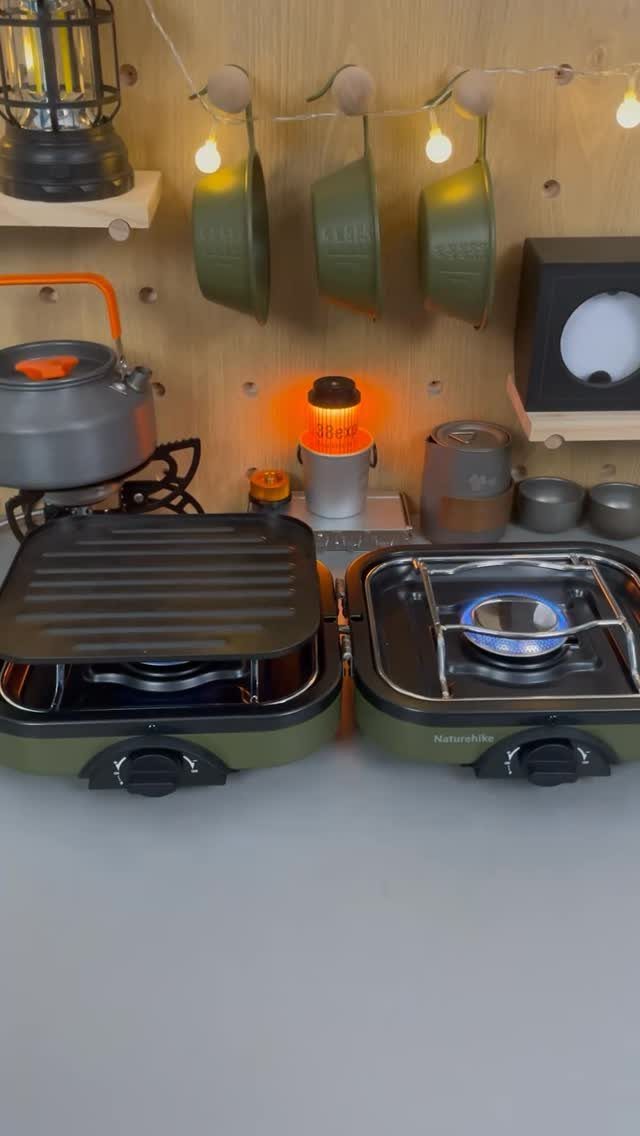 Portable camping stoves and outdoor cooking gear arranged against a wooden wall.
