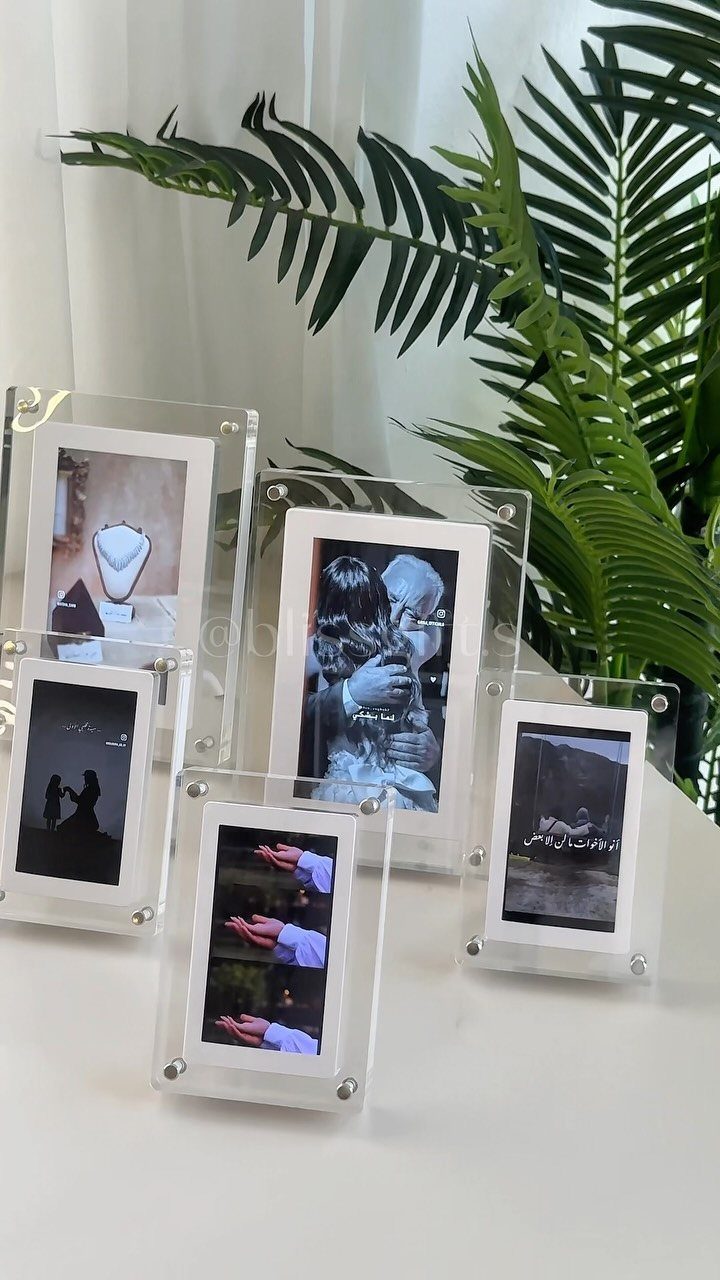 Clear acrylic floating photo frames holding black and white pictures on a white table.
